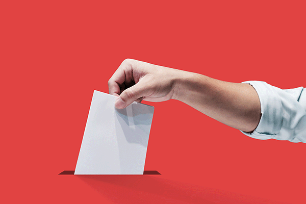 hand inserting ballot in voting box slot