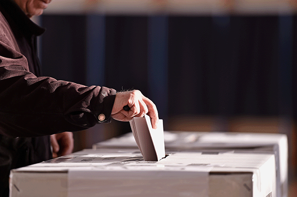 hand inserting vote into ballot box